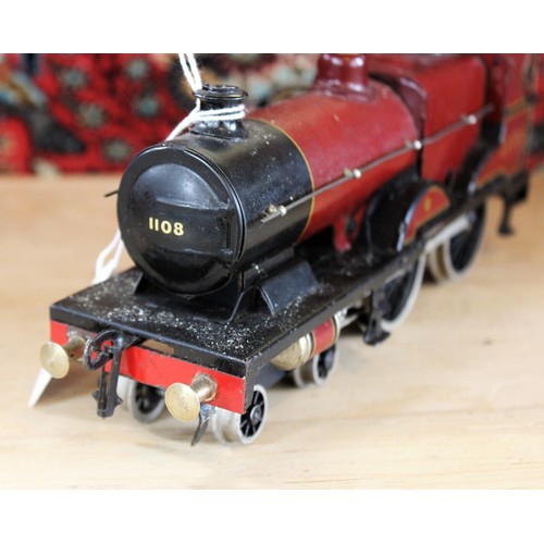 643 - An O Gauge clockwork 4-4-0 locomotive and tender, probably by Bassett-Lowke, in maroon L.M.S. livery... 