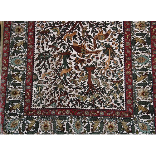 663 - A silkwork rug depicting birds amongst trees, within a repeating foliate border, 150cm x 107cm, alon... 