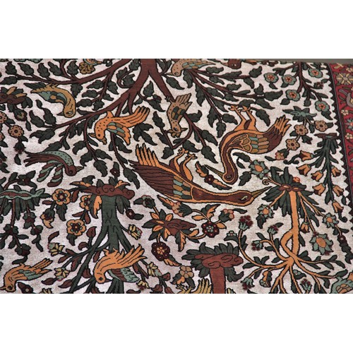 663 - A silkwork rug depicting birds amongst trees, within a repeating foliate border, 150cm x 107cm, alon... 