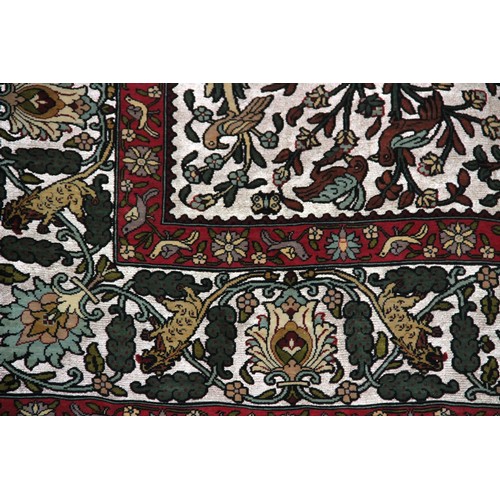 663 - A silkwork rug depicting birds amongst trees, within a repeating foliate border, 150cm x 107cm, alon... 