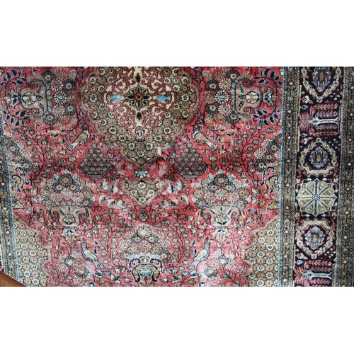 664 - A Persian pattern silkwork rug, the central green medallion on a red ground enclosed by foliate urns... 