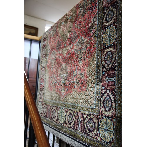 664 - A Persian pattern silkwork rug, the central green medallion on a red ground enclosed by foliate urns... 