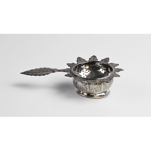 103 - A middle eastern white metal tea strainer and stand, the strainer with with pierced circular bowl, p... 