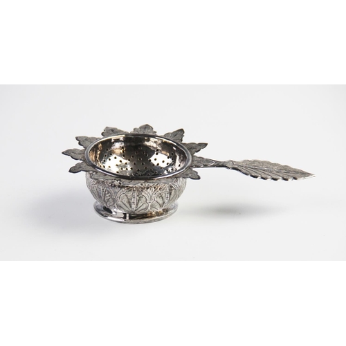 103 - A middle eastern white metal tea strainer and stand, the strainer with with pierced circular bowl, p... 