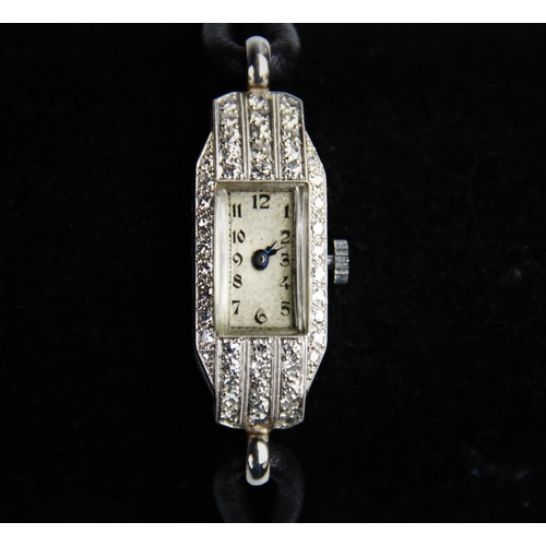 126 - An Art Deco diamond set platinum wristwatch, the rectangular cream with Arabic numerals, set to a to... 