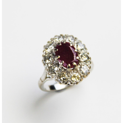 175 - A ruby and diamond cluster ring, comprising a central oval mixed cut ruby measuring 11mm x 8mm, claw... 