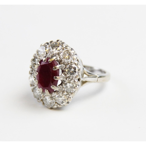 175 - A ruby and diamond cluster ring, comprising a central oval mixed cut ruby measuring 11mm x 8mm, claw... 