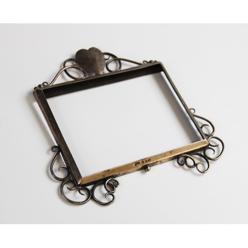 22A - An Arts Crafts silver photograph frame, Birmingham 1897, the rectangular frame with heart shaped sur... 