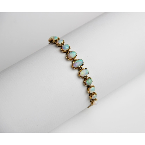 245 - An opal line bracelet, comprising eleven oval opal cabochons measuring between 5mm x 4mm and 10mm x ... 