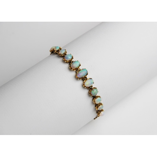 245 - An opal line bracelet, comprising eleven oval opal cabochons measuring between 5mm x 4mm and 10mm x ... 