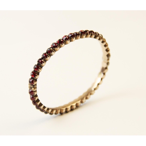 252 - A 19th century garnet set bangle, designed as a single row of forty rose cut garnets, all claw set t... 