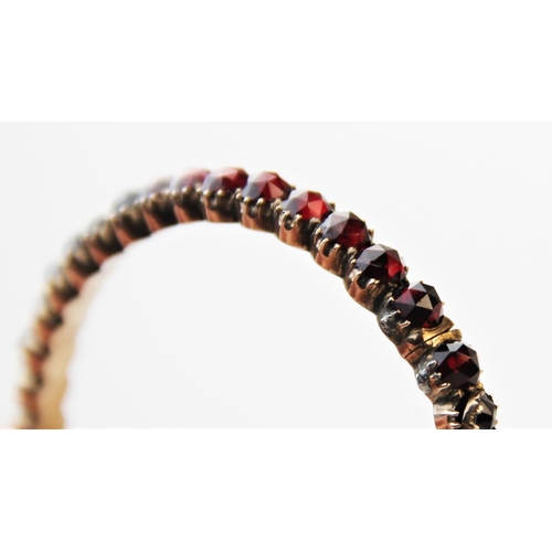 252 - A 19th century garnet set bangle, designed as a single row of forty rose cut garnets, all claw set t... 