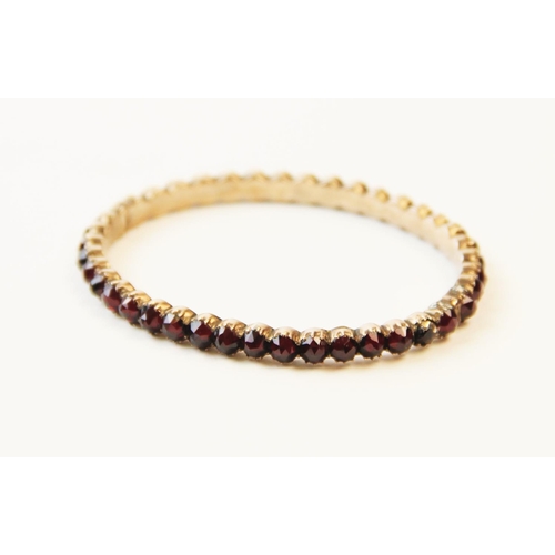 252 - A 19th century garnet set bangle, designed as a single row of forty rose cut garnets, all claw set t... 