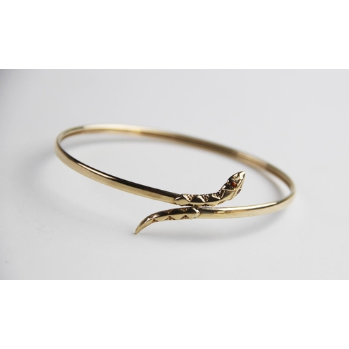 269 - A 9ct gold snake bangle, the plain polished oval bangle with stylised snake head and tail, with two ... 