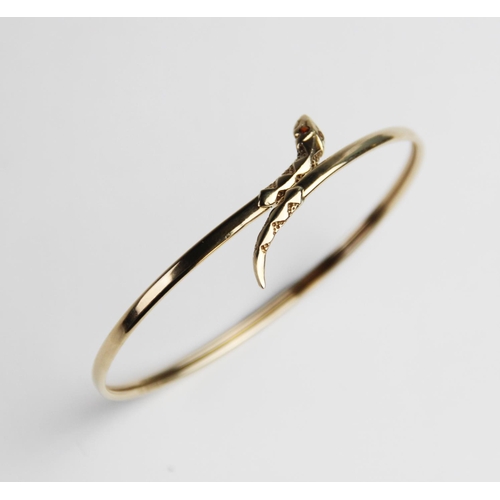 269 - A 9ct gold snake bangle, the plain polished oval bangle with stylised snake head and tail, with two ... 