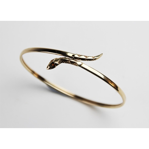 269 - A 9ct gold snake bangle, the plain polished oval bangle with stylised snake head and tail, with two ... 