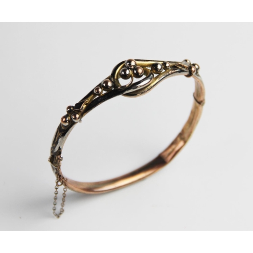 275 - A Victorian yellow metal hinged bangle, the front section designed as a three-leaf clover to a twist... 