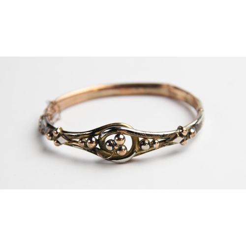 275 - A Victorian yellow metal hinged bangle, the front section designed as a three-leaf clover to a twist... 