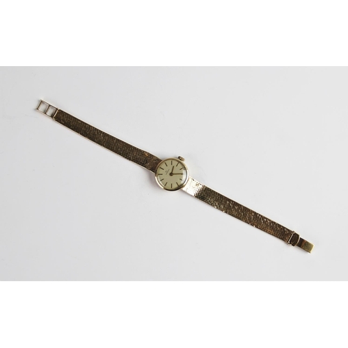 133 - A lady's vintage 9ct gold Garrard wristwatch, the round cream dial with baton markers, set to a plai... 