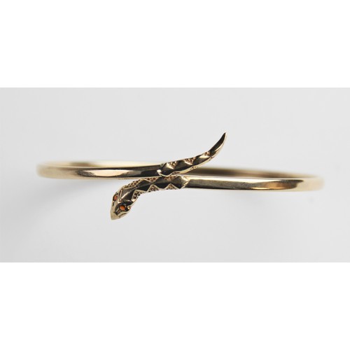 269 - A 9ct gold snake bangle, the plain polished oval bangle with stylised snake head and tail, with two ... 