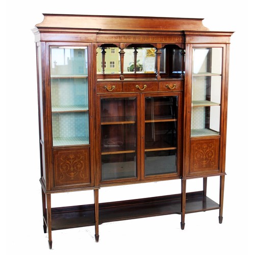 852 - An Edwardian inlaid mahogany inverted breakfront display cabinet, the shaped pediment above a centra... 