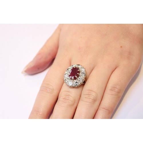 175 - A ruby and diamond cluster ring, comprising a central oval mixed cut ruby measuring 11mm x 8mm, claw... 