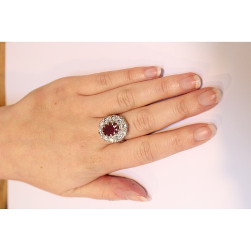 175 - A ruby and diamond cluster ring, comprising a central oval mixed cut ruby measuring 11mm x 8mm, claw... 