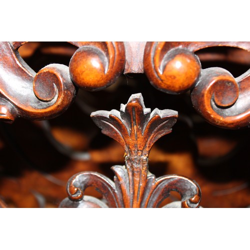 825 - A Victorian figured walnut Canterbury, the outer carved foliate open work dividers flanking a pair o... 