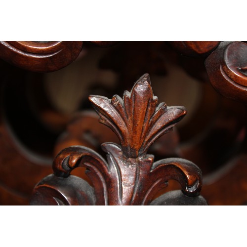 825 - A Victorian figured walnut Canterbury, the outer carved foliate open work dividers flanking a pair o... 