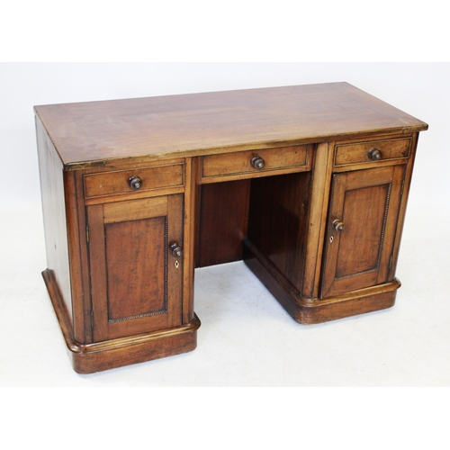 1008 - A Victorian mahogany kneehole desk/dressing table, the cleated rectangular top above an inverted cen... 