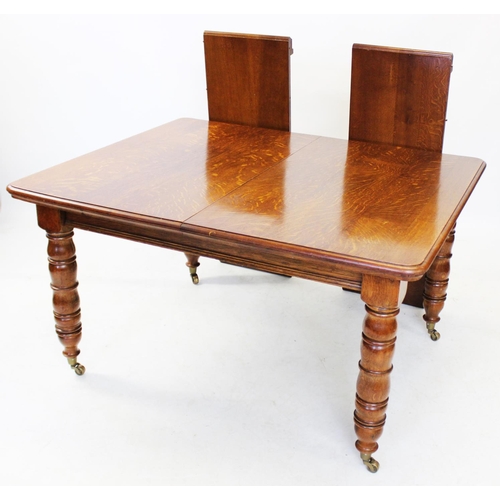 1029 - An early 20th century golden oak extending dining table, the rectangular top with moulded and rounde... 