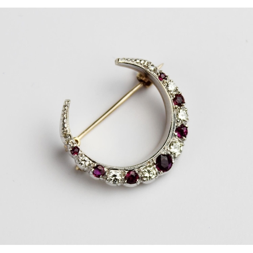 200 - A diamond and ruby set crescent brooch, comprising eight graduated round brilliant cut diamonds and ... 