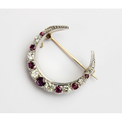 200 - A diamond and ruby set crescent brooch, comprising eight graduated round brilliant cut diamonds and ... 