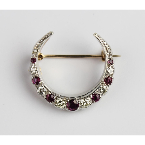 200 - A diamond and ruby set crescent brooch, comprising eight graduated round brilliant cut diamonds and ... 