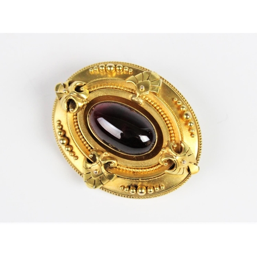 275 - A Victorian Etruscan style memorial brooch, comprising a central garnet cabochon measuring 19mm x 12... 