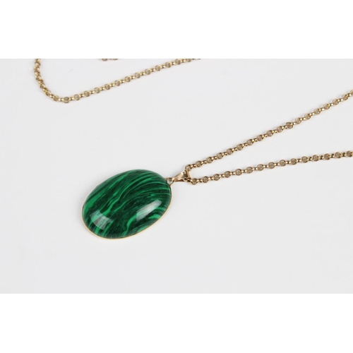 279 - A malachite pendant on chain, the central polished oval malachite cabochon measuring 29mm x 20mm, se... 