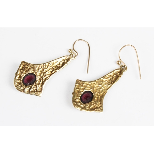 292 - A pair of Art Nouveau style garnet drop earrings, each comprising a polished oval garnet cabochon (m... 