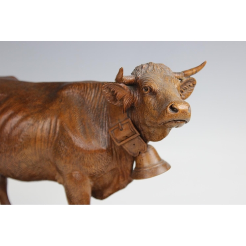 391 - A Swiss carving in the manner of Johann Huggler of  Brienz, modelled as a cow with a bell around its... 