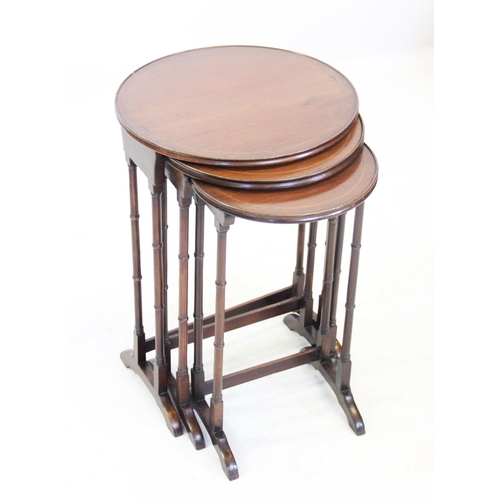 1041 - An Edwardian mahogany nest of tea tables, each with a circular tray top raised upon slender ring tur... 