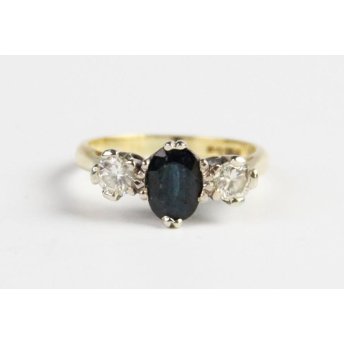 245 - A diamond and sapphire three-stone ring, the central oval mixed cut sapphire measuring 7mm x 5mm, wi... 