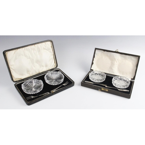 96 - A cased pair of cut glass butter dishes, each 8.7cm wide, each with accompanying silver butter knive... 