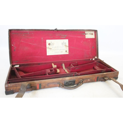 412 - An Adams & Co leather double gun case, of typical form with leather over-straps and central sprung l... 