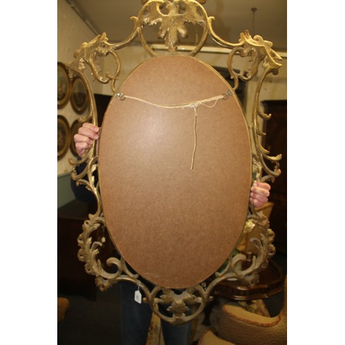 1027 - A late 19th/early 20th century French Rococo style gilt wood wall mirror, the oval mirror plate encl... 