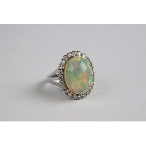 192 - An opal and diamond cluster ring, the central oval natural opal cabochon (measuring 15.2mm x 11.4mm)... 