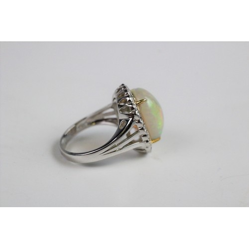 192 - An opal and diamond cluster ring, the central oval natural opal cabochon (measuring 15.2mm x 11.4mm)... 