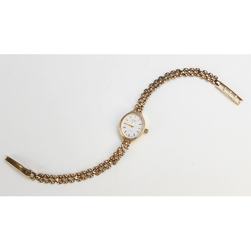 130 - A Lady's 9ct gold Rotary wristwatch, the white oval dial with baton markers, set to a plain polished... 