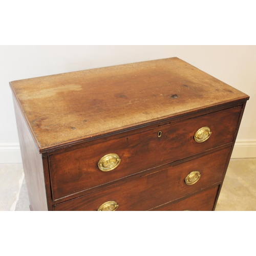 560 - An early 19th century mahogany chest of drawers, formed as three drawers set with oval brass handles... 