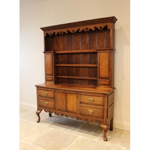 568 - A George III style oak high back dresser, mid 20th century, with shaped frieze over three enclosed s... 