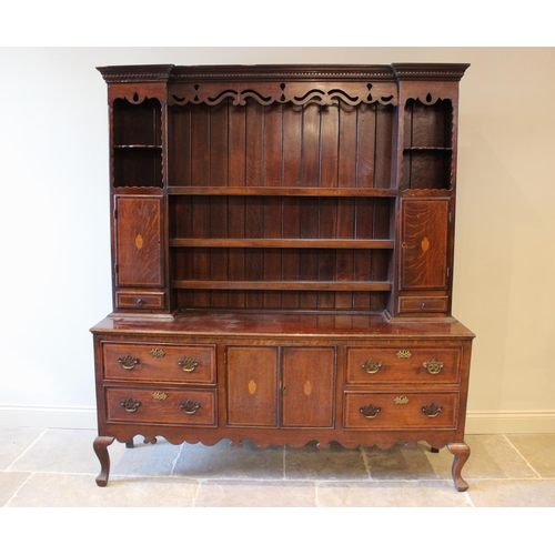 568 - A George III style oak high back dresser, mid 20th century, with shaped frieze over three enclosed s... 