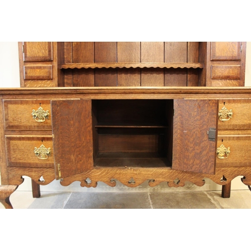 568 - A George III style oak high back dresser, mid 20th century, with shaped frieze over three enclosed s... 